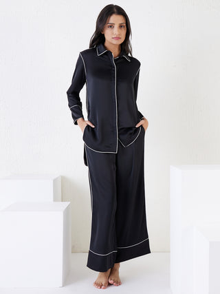 a women standing a wearing a black silky contemporary pant set made of signature satin
